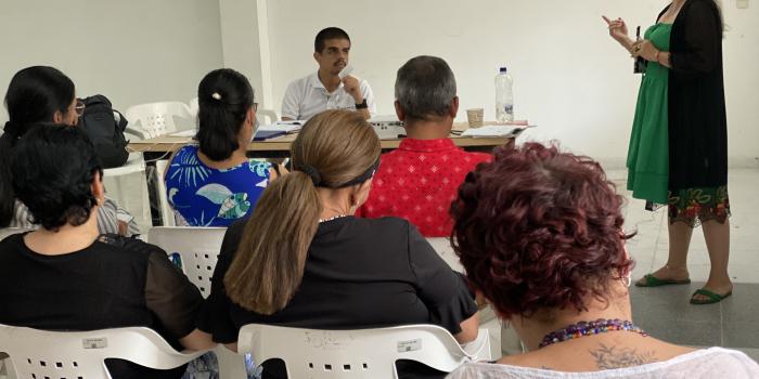 Grupo de personas sentadas prestando atención a mujer que expone ideas