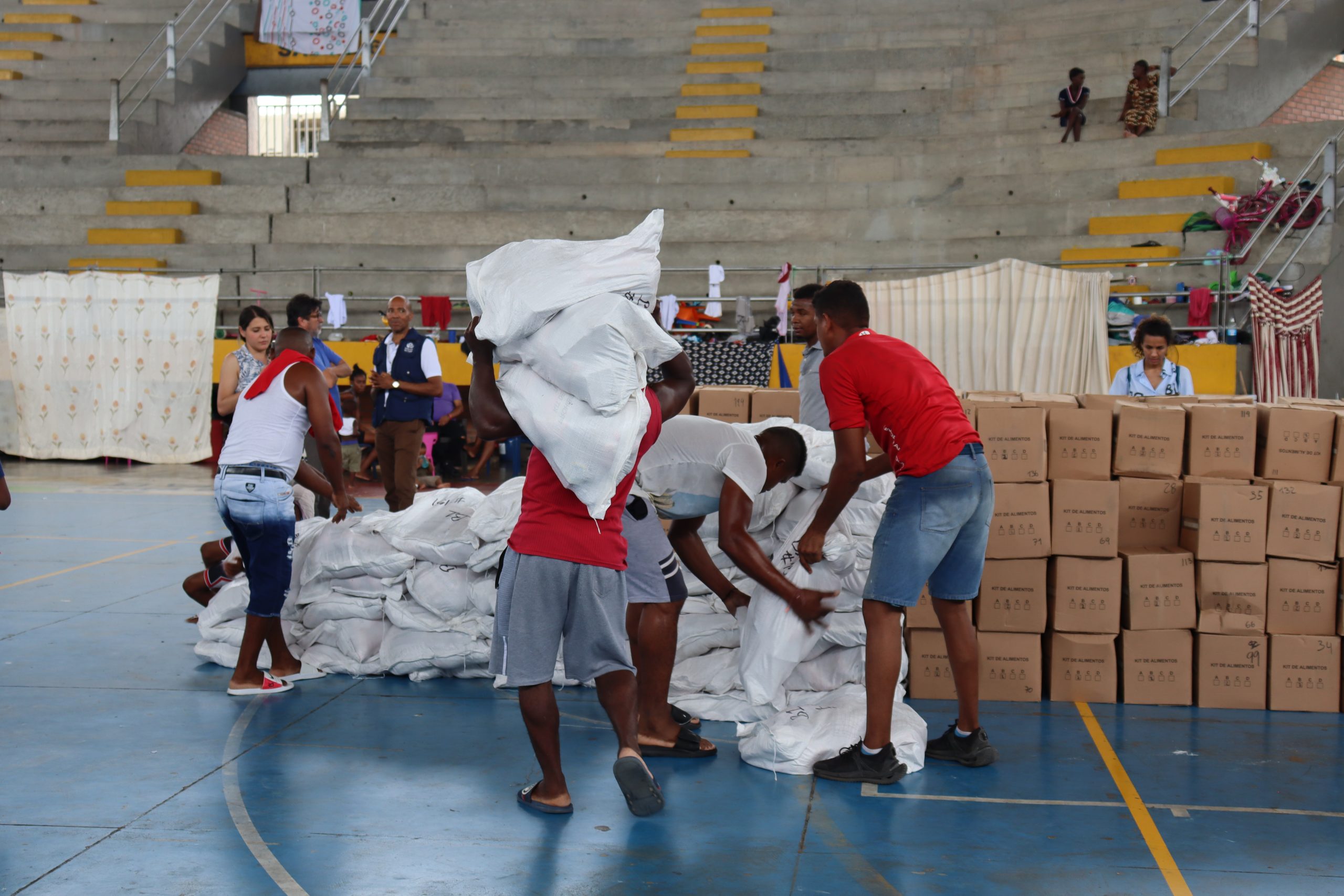 Hombres cargando bultos de color blanco con ayudas humanitarias para la comunidad del Bajo del Calima