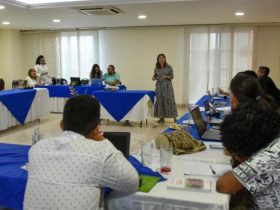 Mujer hablando a personas que se encuentran en recinto