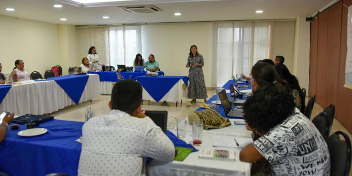 Mujer hablando a personas que se encuentran en recinto