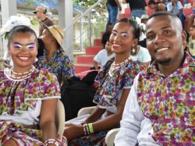 2 mujeres y hombre joven sonriendo a la cámara vestidos con atuendos de folclor