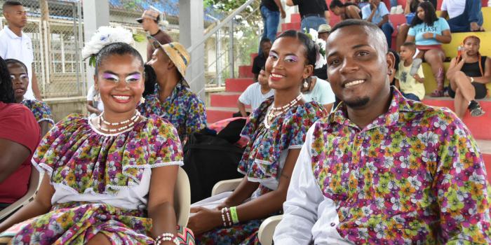 2 mujeres y hombre joven sonriendo a la cámara vestidos con atuendos de folclor