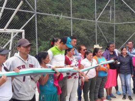 Grupo de personas sosteniendo cinta larga en cancha de futbol