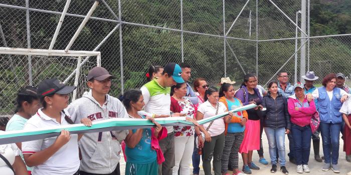 Grupo de personas sosteniendo cinta larga en cancha de futbol