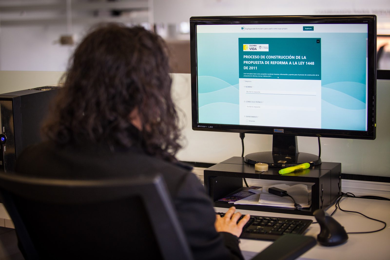 Persona sentada en frente de computador diligenciando formulario de la propuesta de reforma a la ley 1448