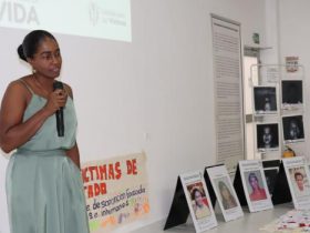 Mujer con micrófono hablando en acto simbólico con fotos de víctimas