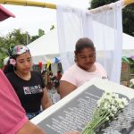 Hombre poniendo flores sobre monumento de memoria