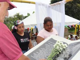 Hombre poniendo flores sobre monumento de memoria