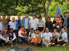 22 personas posando para un foto sobre la orilla de un rio