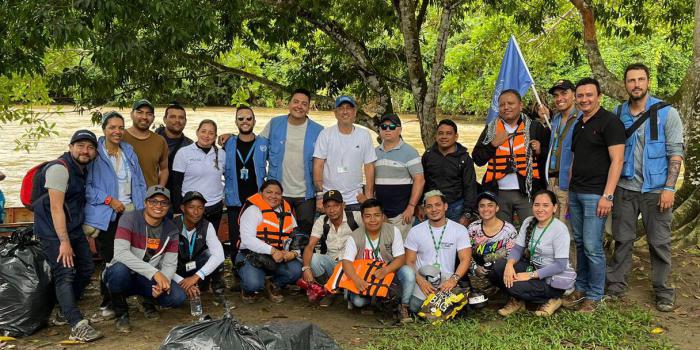 22 personas posando para un foto sobre la orilla de un rio