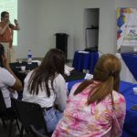 Mujer hablando por micrófono frente a un grupo de personas