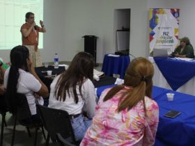 Mujer hablando por micrófono frente a un grupo de personas