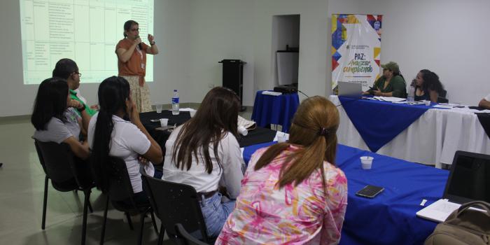 Mujer hablando por micrófono frente a un grupo de personas