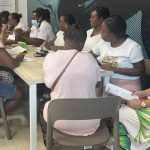 Mujeres afrodescendientes sentadas en mesa socializando entre ellas