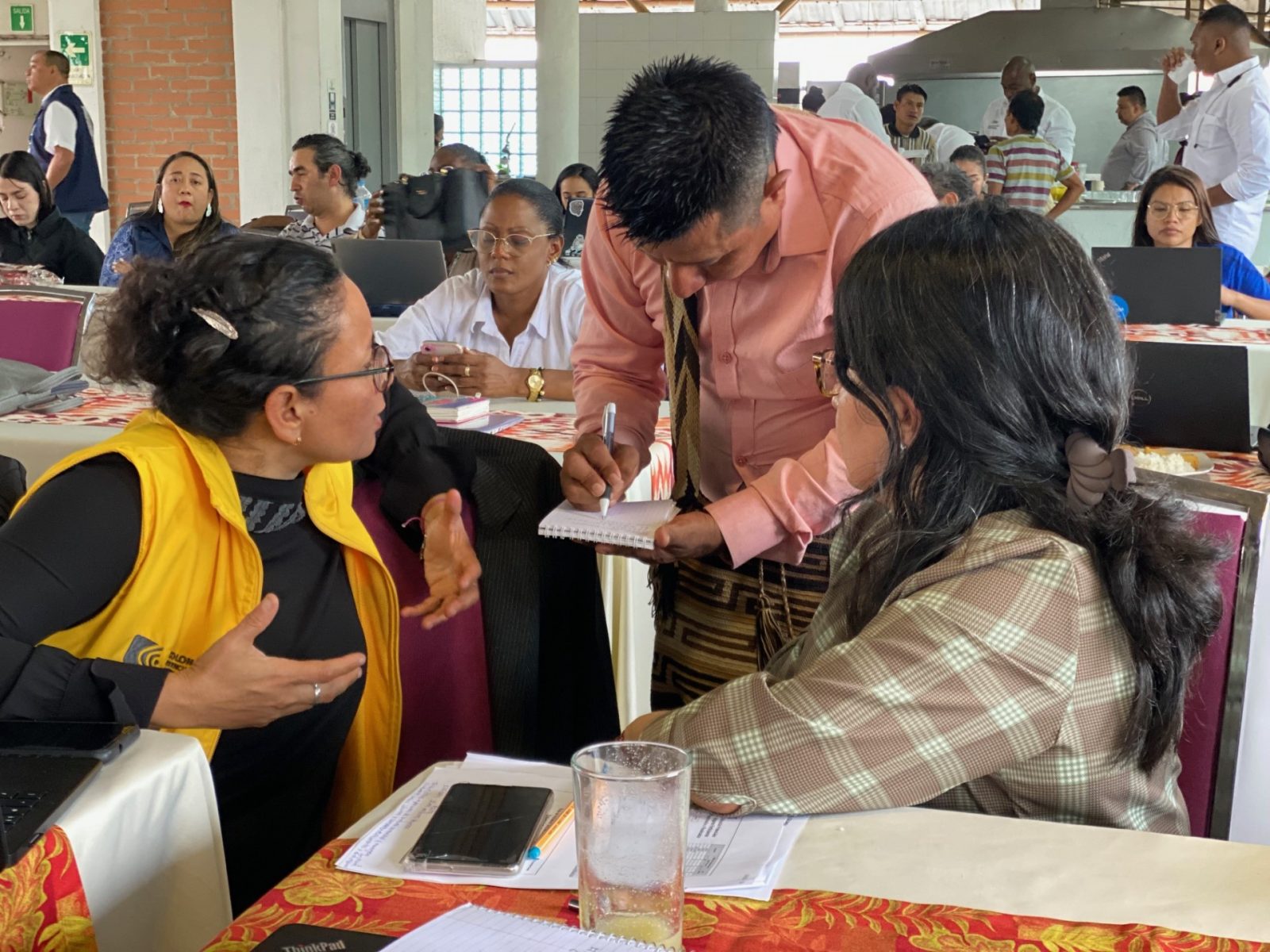 Indígena emberá escribiendo en una libreta información que le suministran
