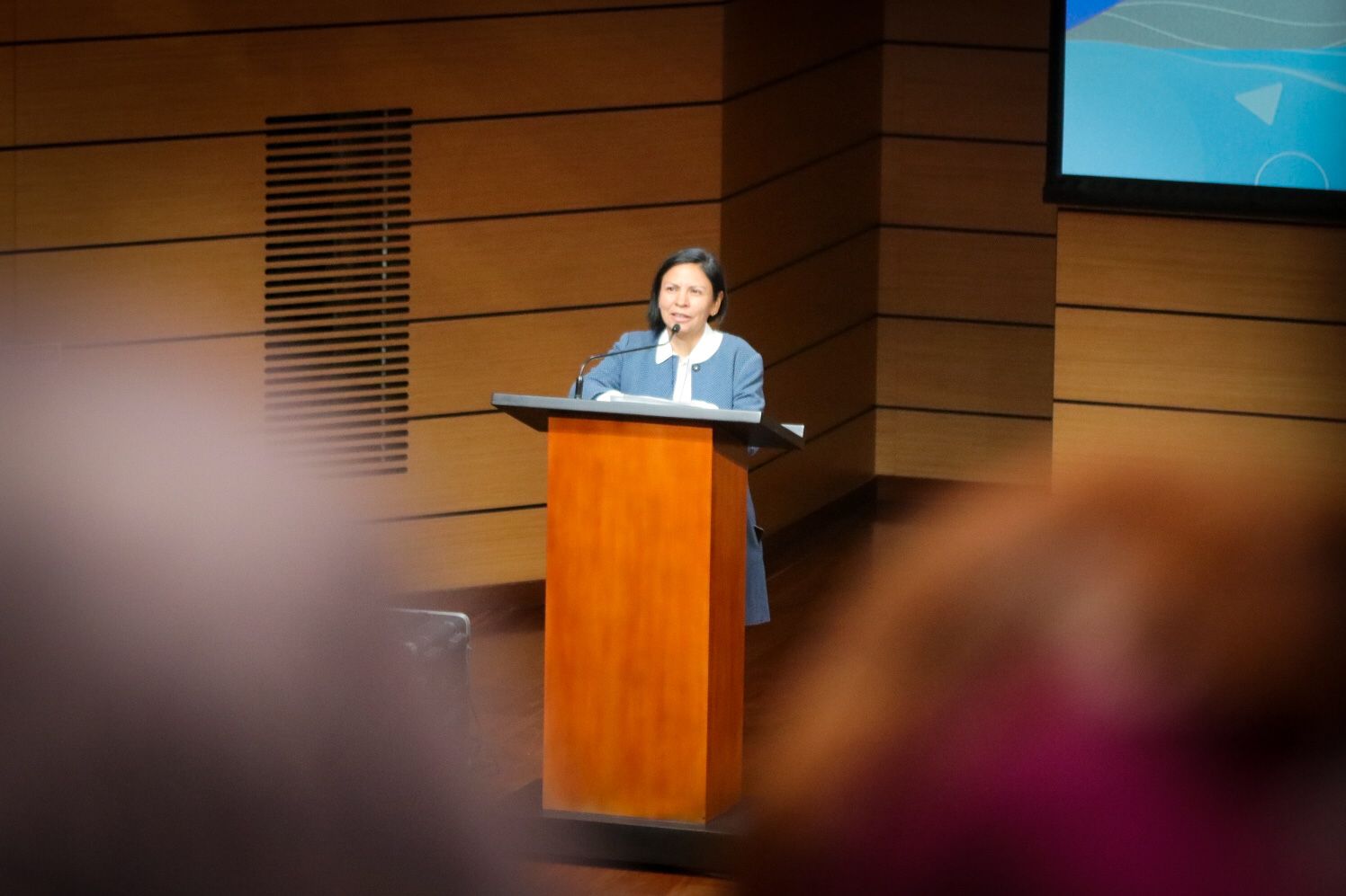 Patricia Tobón en atril hablando por micrófono en auditorio