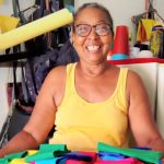 Mujer de tez morena sonriendo desde su taller de confección