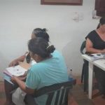 Grupo de personas reunidas con funcionarios de La Unidad diligenciando formularios