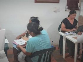 Grupo de personas reunidas con funcionarios de La Unidad diligenciando formularios