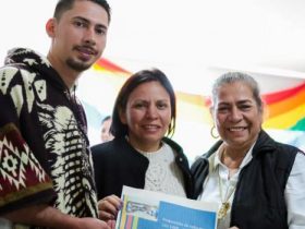 Directora Paula Tobón sosteniendo diploma de mujer y hombre que participaron en la Mesa Nacional de Victimas