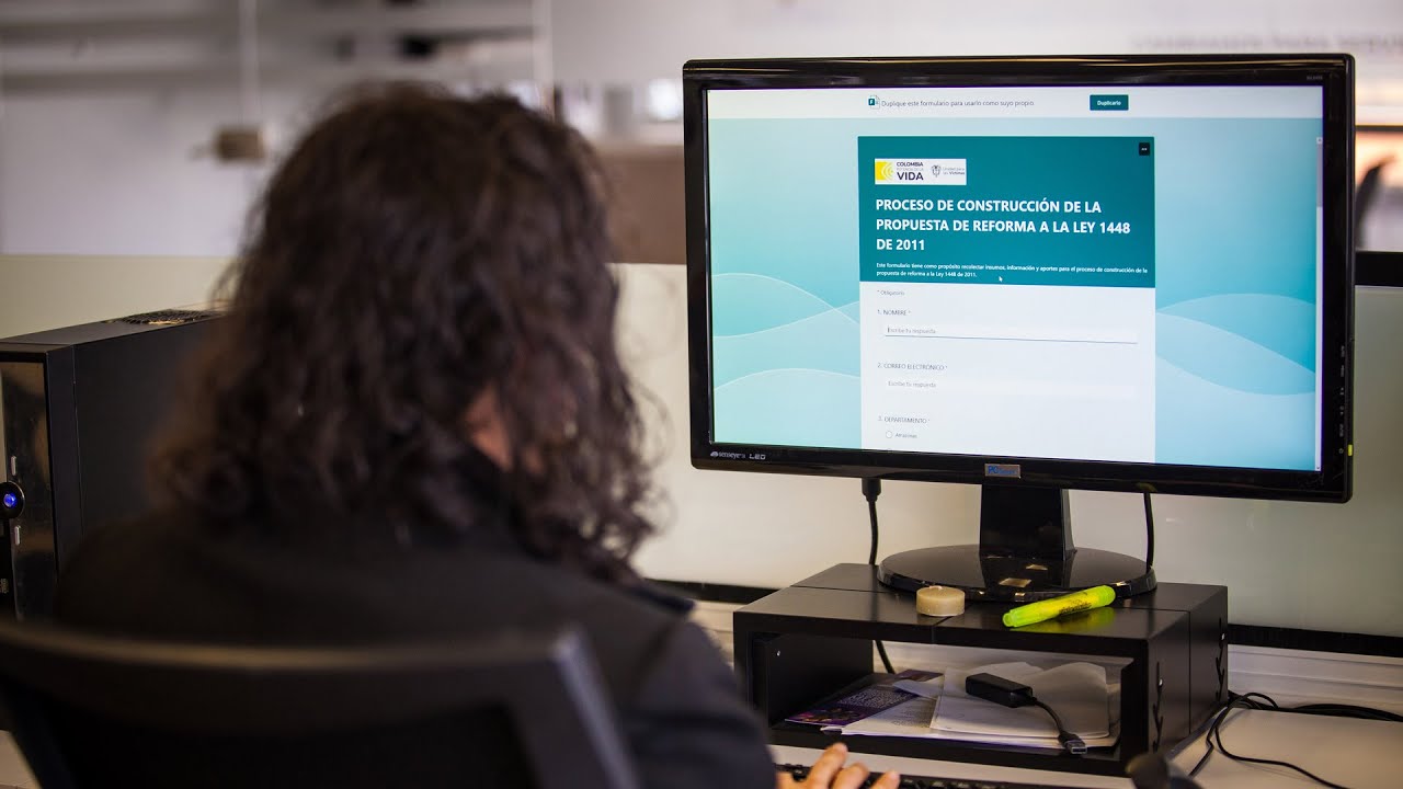 Persona sentada en frente de un computador con formulario del proceso de construcción de la propuesta de reforma a la ley 1448