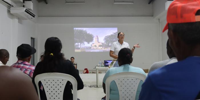 Mujuer exponiendo con proyector videobean a grupo de personas de San Onofre