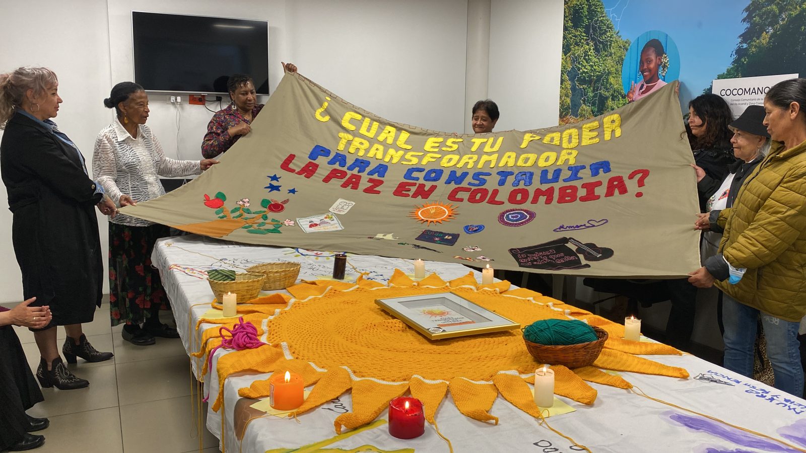 Grupo de personas sosteniendo tejido con símbolo del poder transformador para construir la paz en Colombia