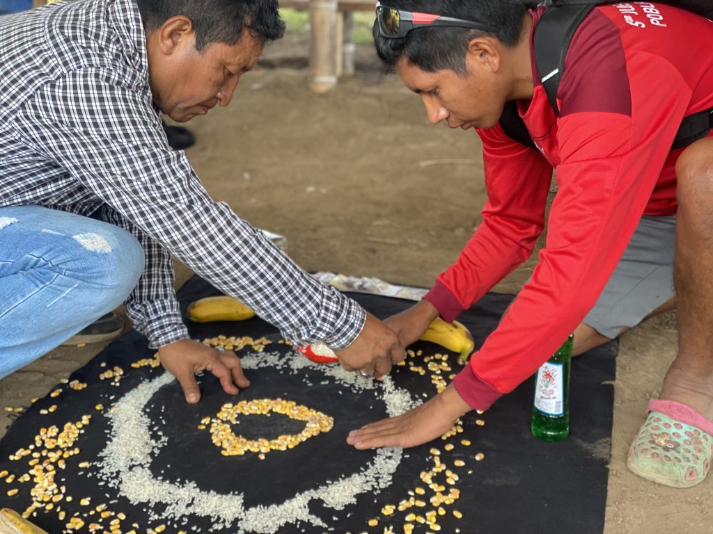 Dos indigenas de la comunidad Karabidrúa  regando semillas sobre manta negra