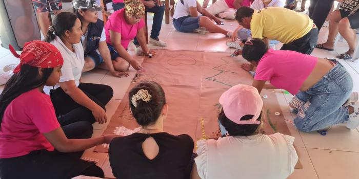 Grupos de personas sentadas en el piso haciendo cartelera