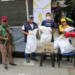 Grupo de personas recibiendo ayudas humanitarias en tulas blancas y cajas