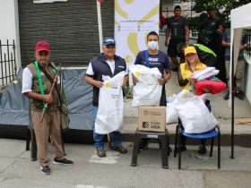 Grupo de personas recibiendo ayudas humanitarias en tulas blancas y cajas