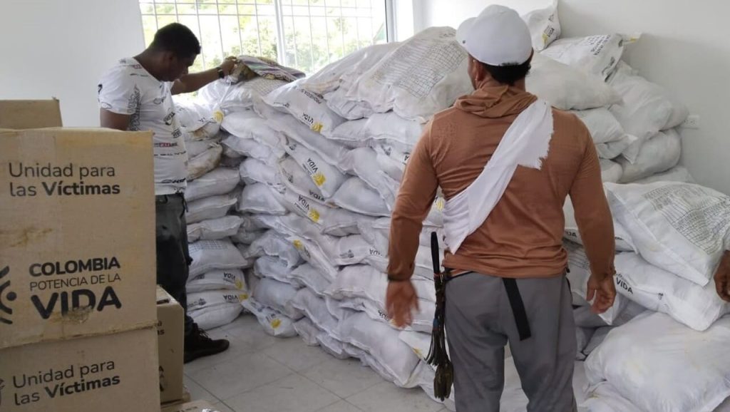 Dos personas en bodega con bultos y cajas de ayuda humanitaria