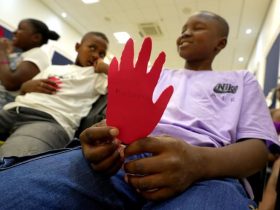 Tres niños sosteniendo una mano roja de carton