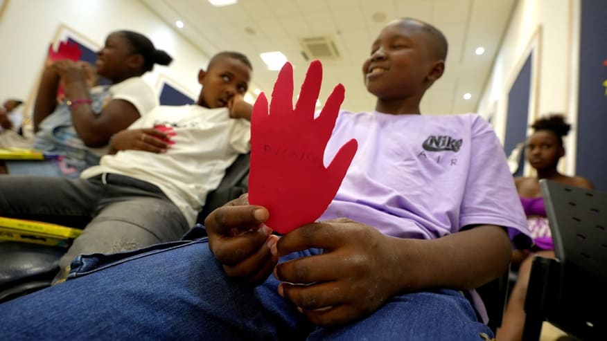 Tres niños sosteniendo una mano roja de carton