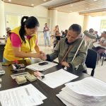 Funcionario con chaleco amarillo entrgando documento a mujer adulta